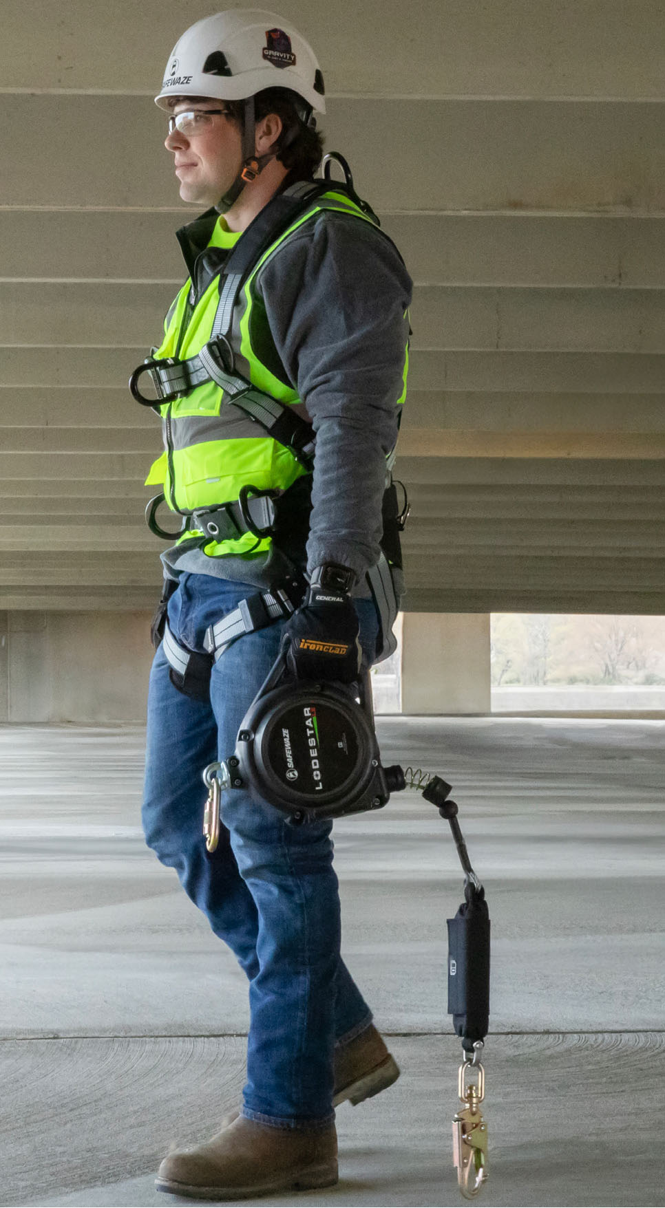 Worker wearing a fall-protection harness and self-retracting device in an industrial work environment