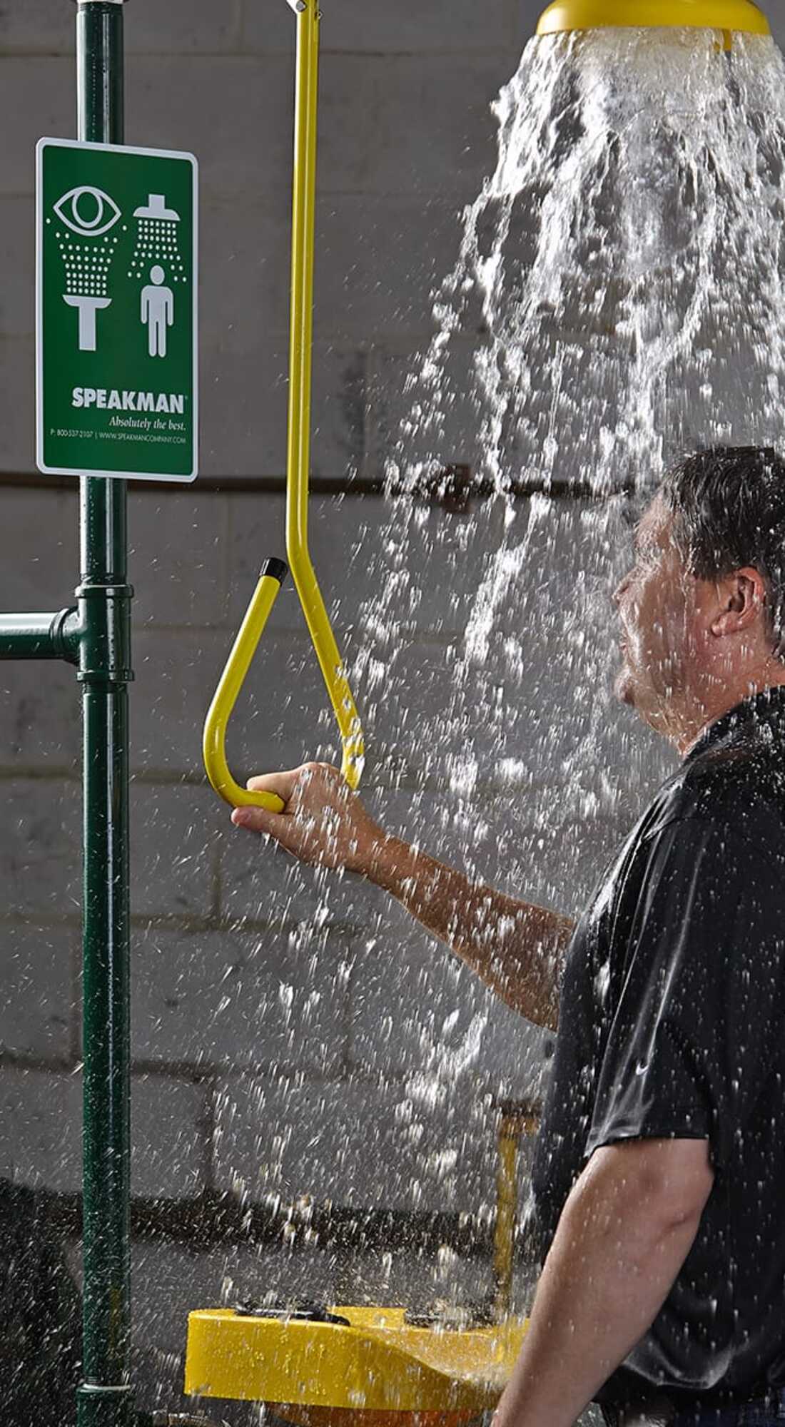 Worker activating a Speakman emergency shower in an industrial facility