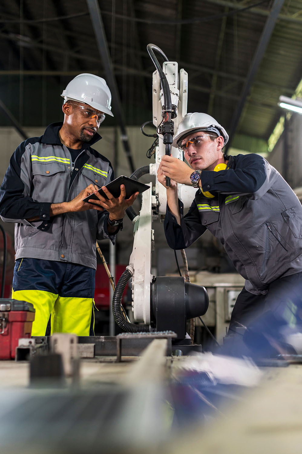 Two industrial workers reviewing equipment and product information on a tablet
